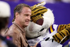 HOUSTON, TEXAS - DECEMBER 27: Head coach Lane Kiffin of the Louisiana State Tigers poses with the mascot before the game against the Houston Cougars during the Kinder's Texas Bowl at NRG Stadium on December 27, 2025 in Houston, Texas. (Photo by Tim Warner/Getty Images)