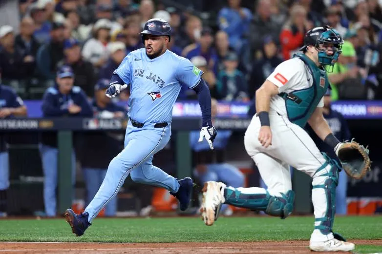 SEATTLE, WASHINGTON - OCTOBER 15: Anthony Santander #25 of the Toronto Blue Jays scores a run past Cal Raleigh #29 of the Seattle Mariners during the fifth inning in game three of the American League Championship Series at T-Mobile Park on October 15, 2025 in Seattle, Washington. (Photo by Steph Chambers/Getty Images)
